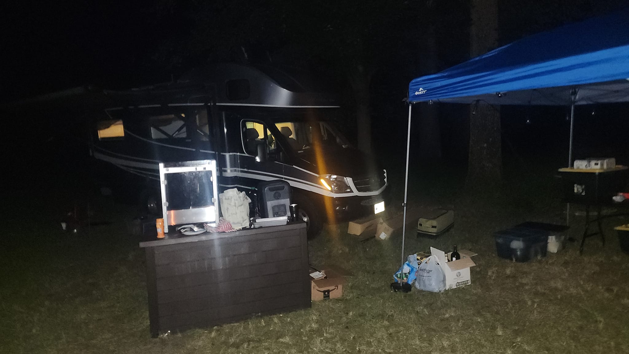 The RV and a blue canopy set up at the edge of the field late at night — Campout 2023