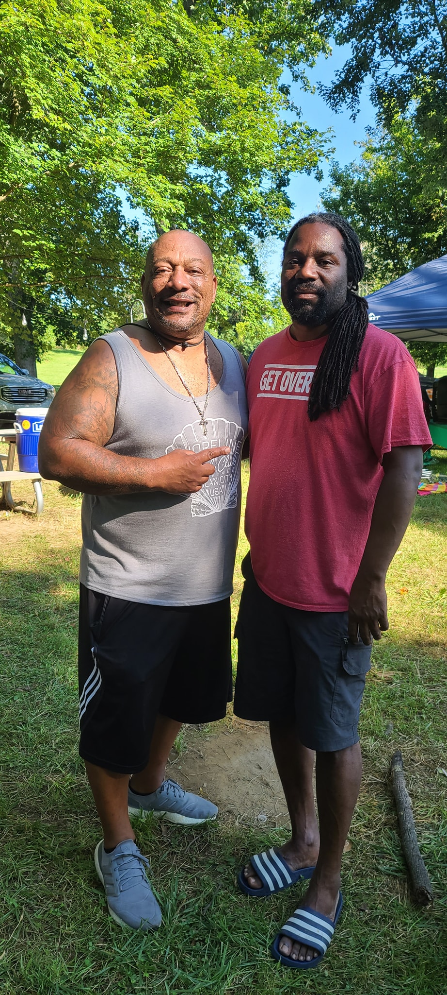 Two men smiling together under the trees at the first campout — Campout 2023