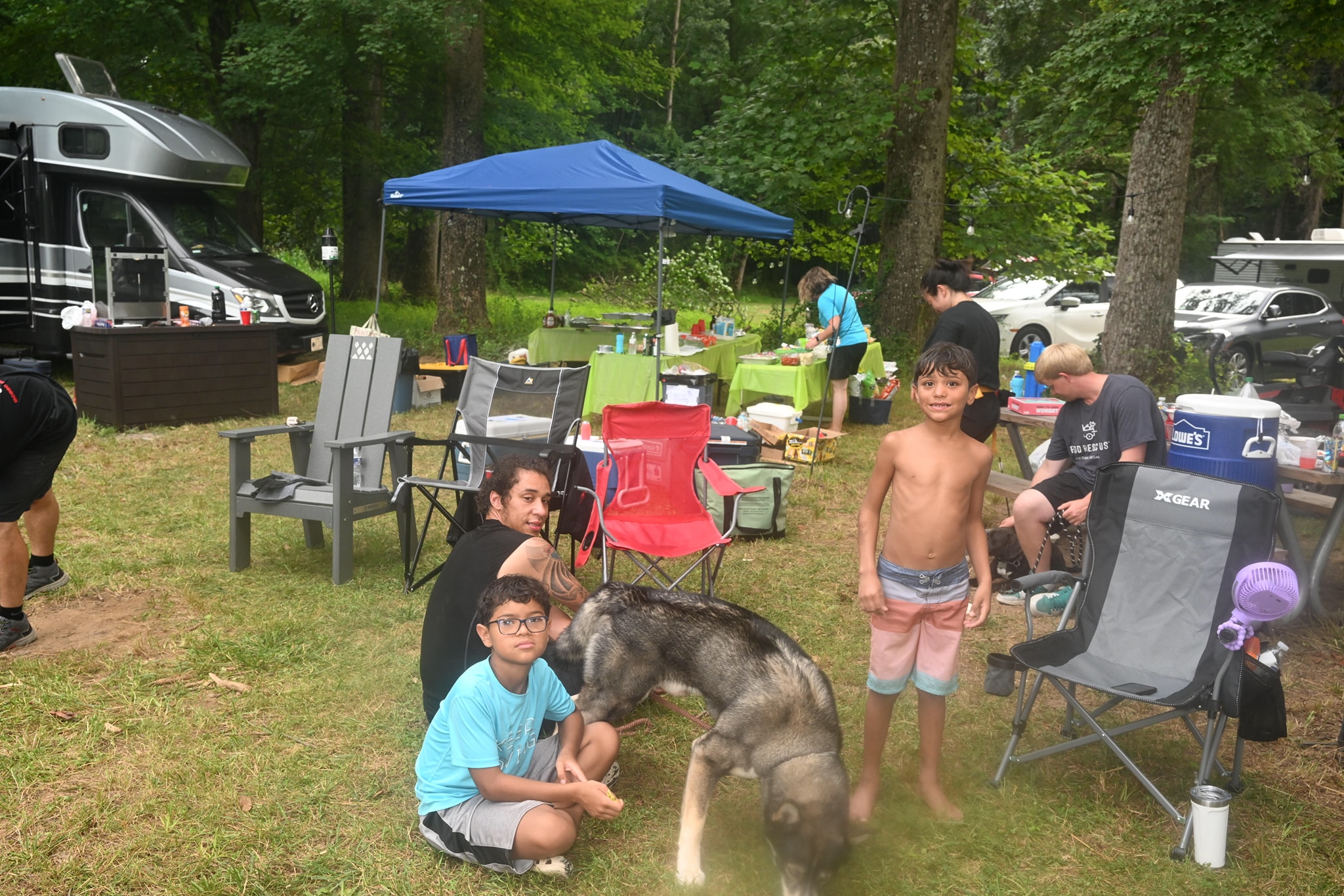 Kids petting a large dog in the campsite with the RV and food table in the background — Campout 2023