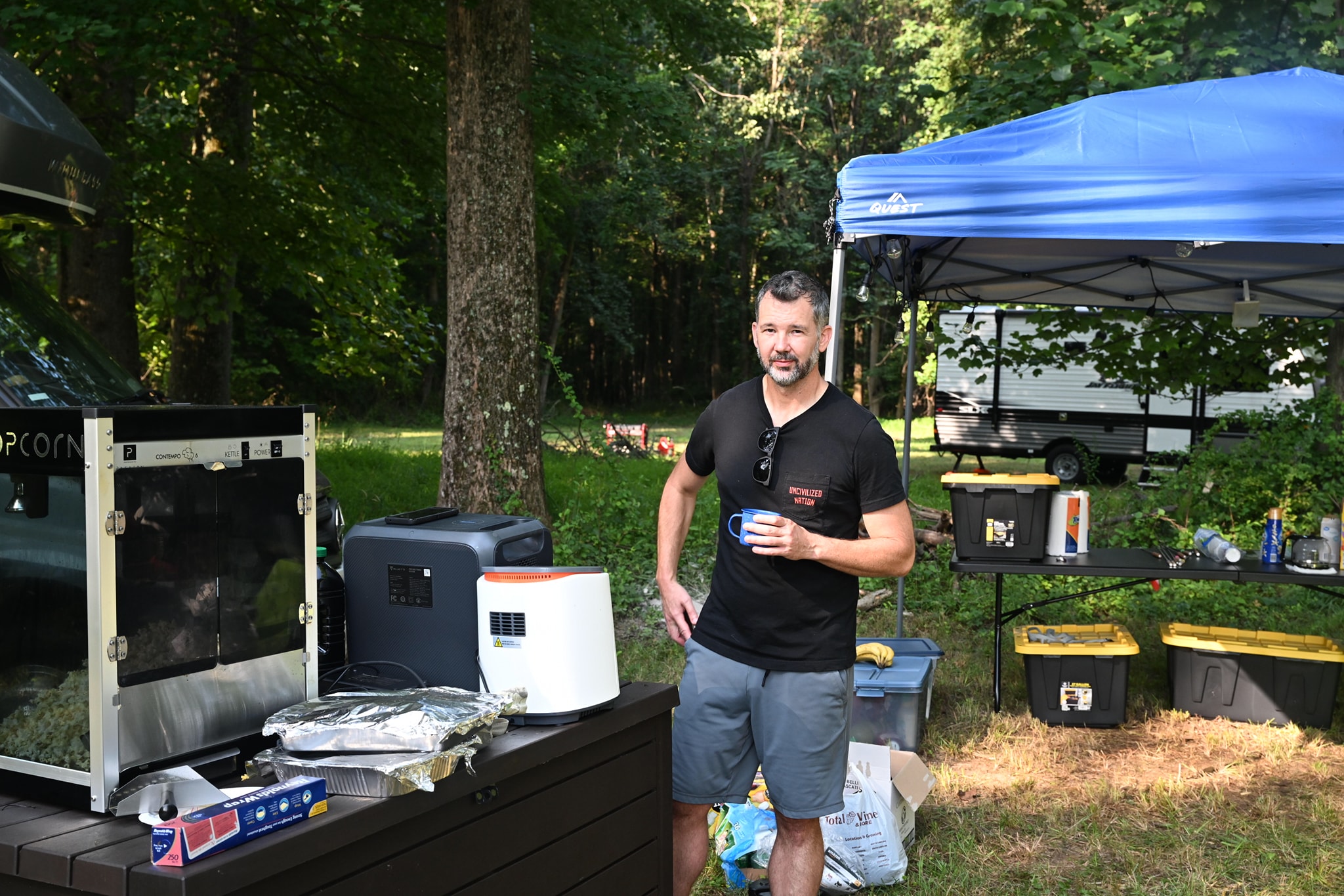 Standing beside the popcorn machine and bar setup under the trees — Campout 2023