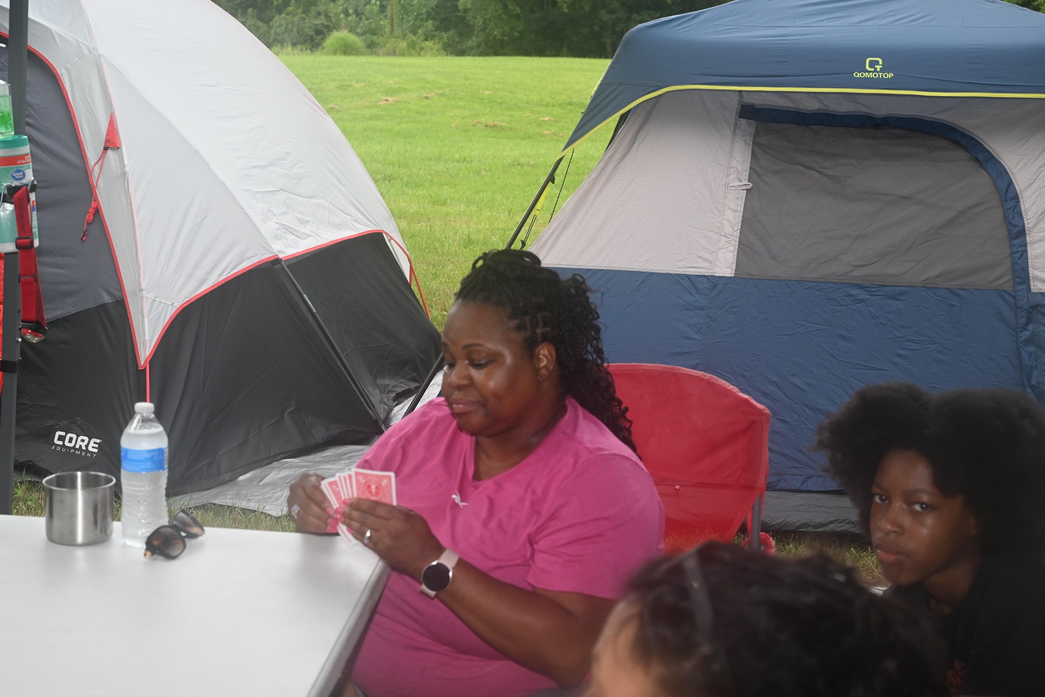 Playing cards at a table between two tents on the campsite — Campout 2023