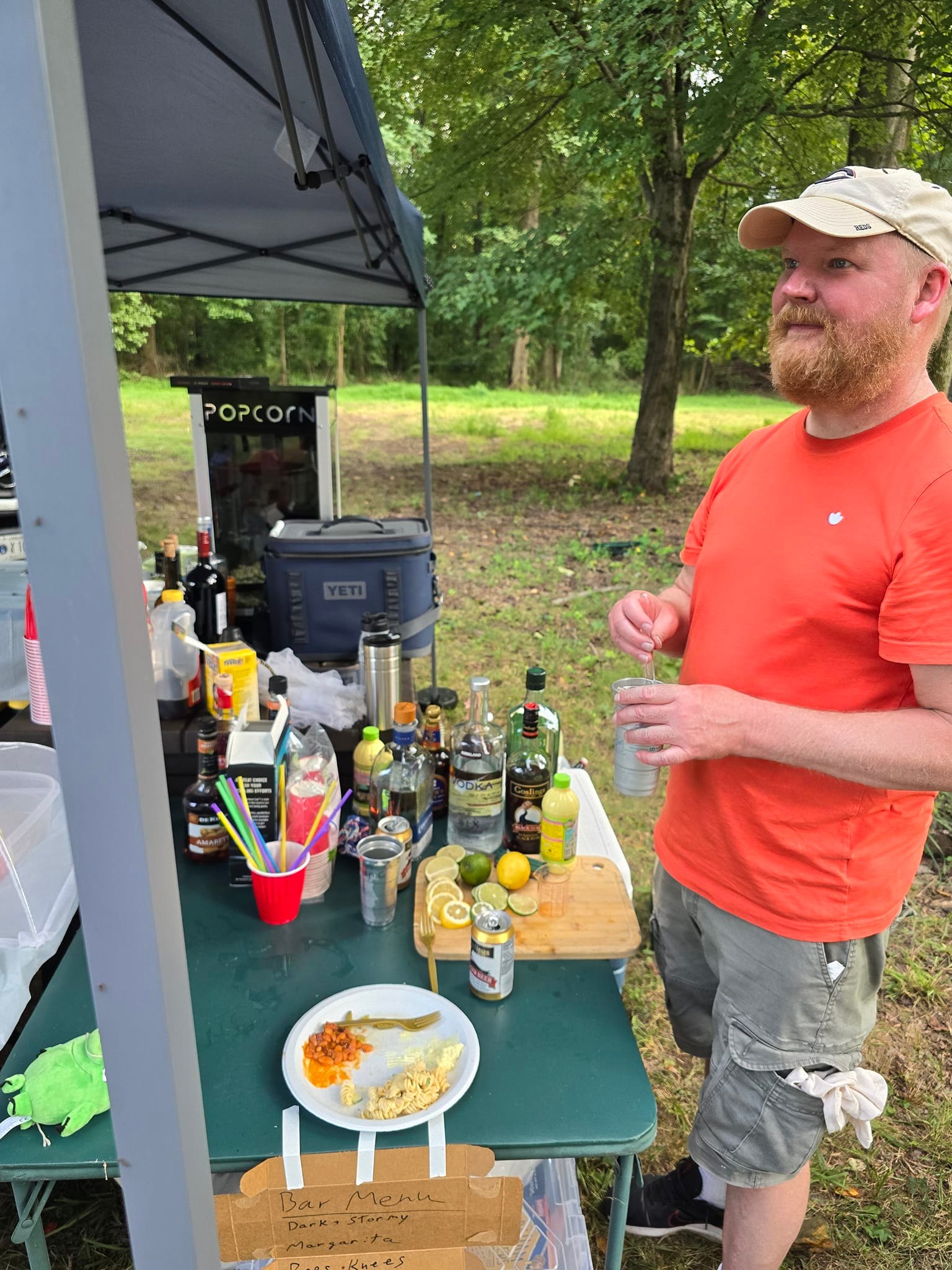 Bartending at the outdoor bar station with liquor bottles and cocktail menu on display — Campout 2024