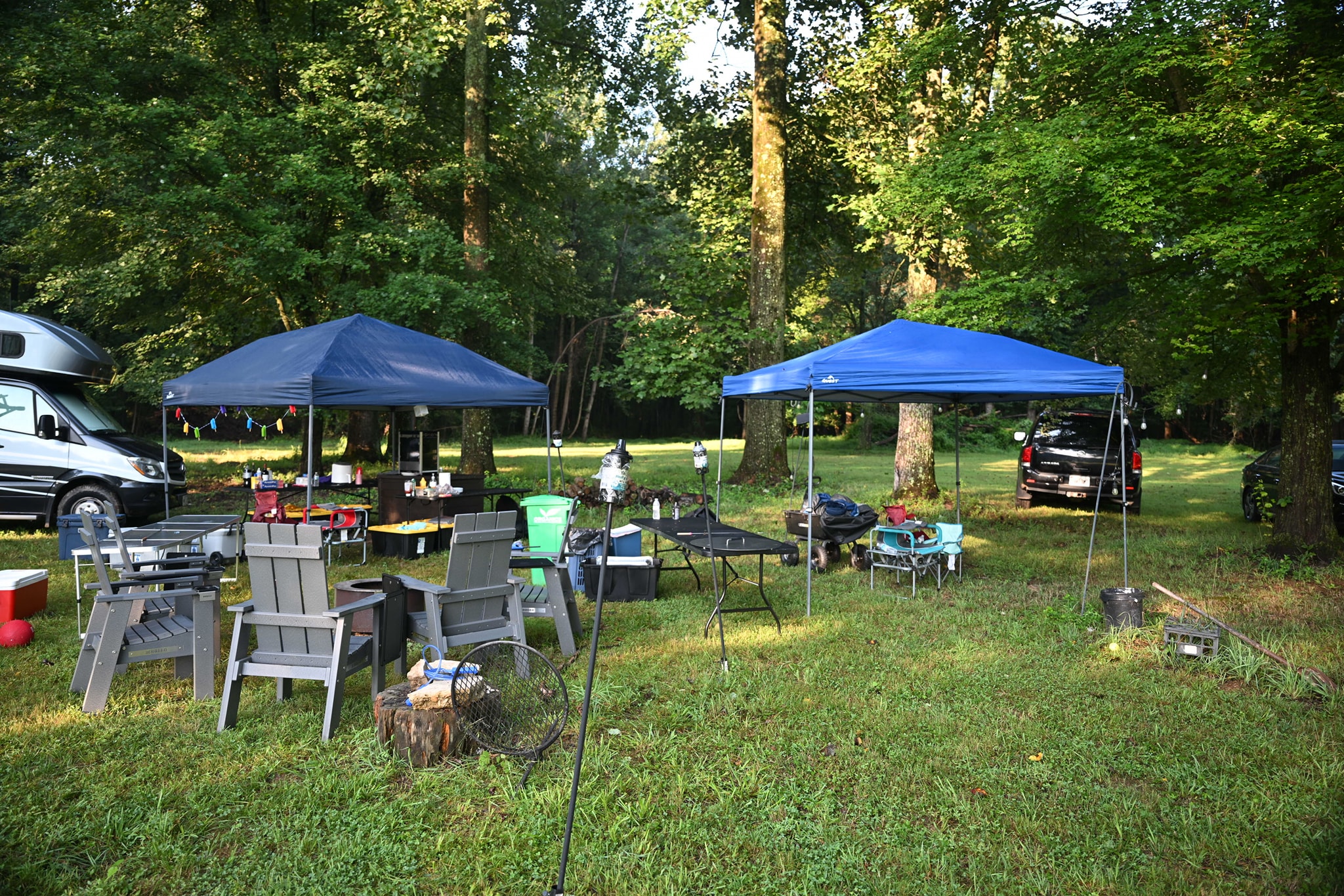 Canopy tents set up in the wooded backyard with tables ready to go — Campout 2024