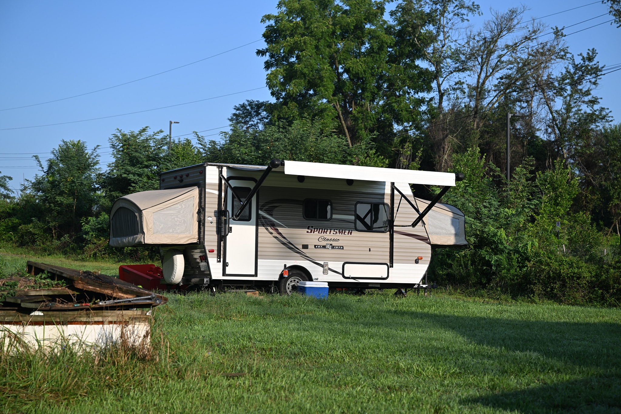 A pop-up camper trailer parked on the grass at the edge of the property — Campout 2024