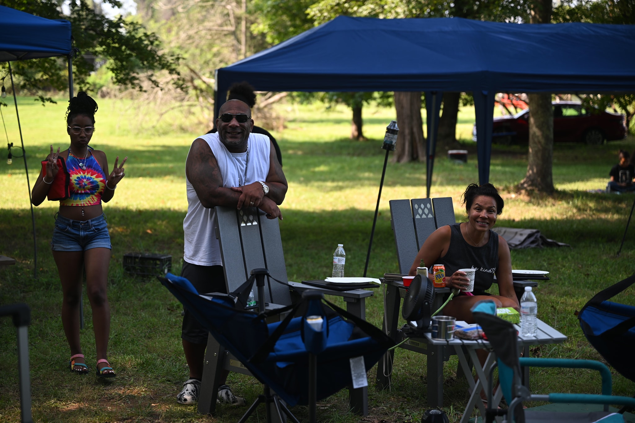 Guests laughing and posing near the camp chairs under the canopy — Campout 2024
