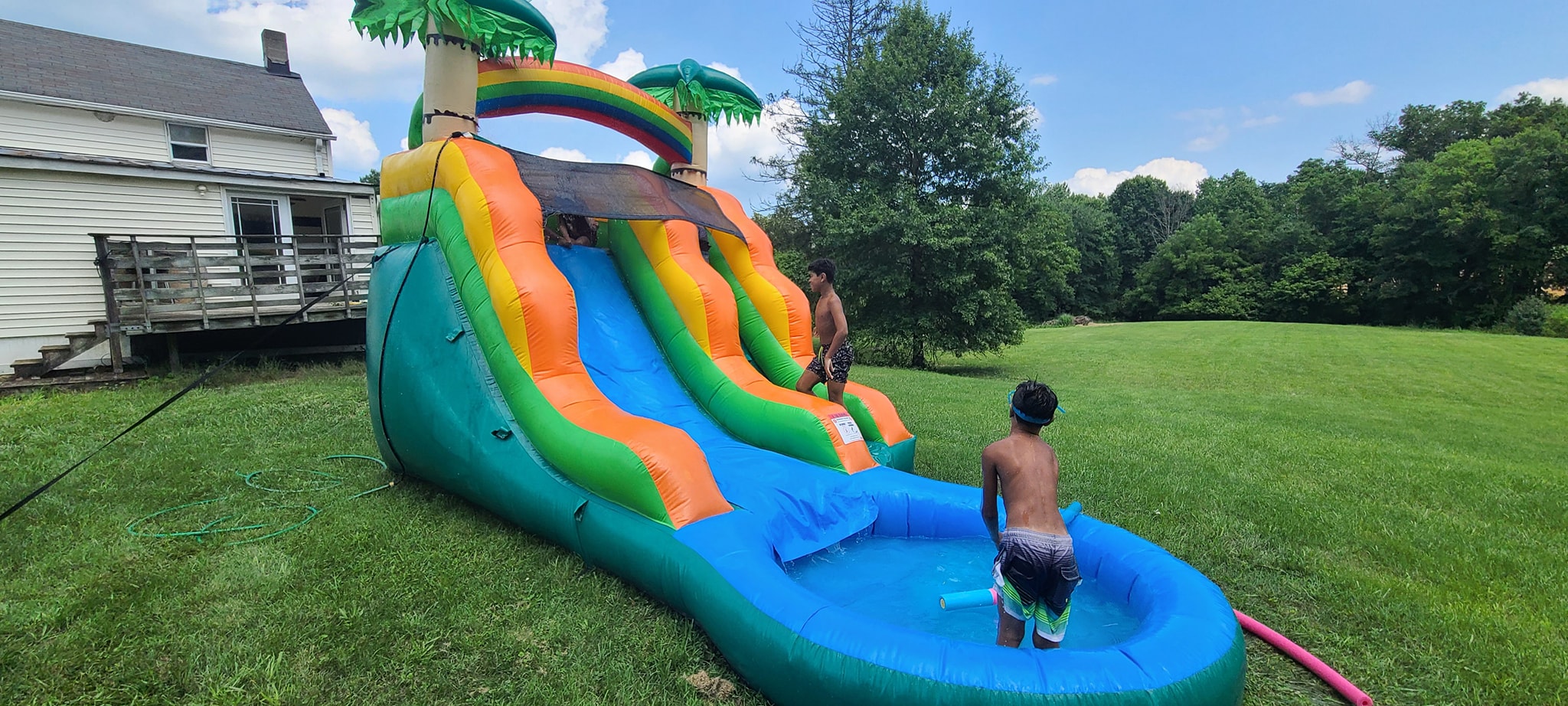 Kids playing at the inflatable water slide in the sunny backyard — Campout 2024