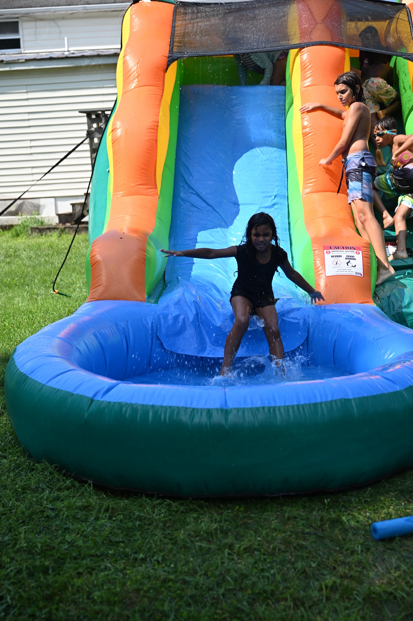A kid riding the water slide straight into the pool — Campout 2024