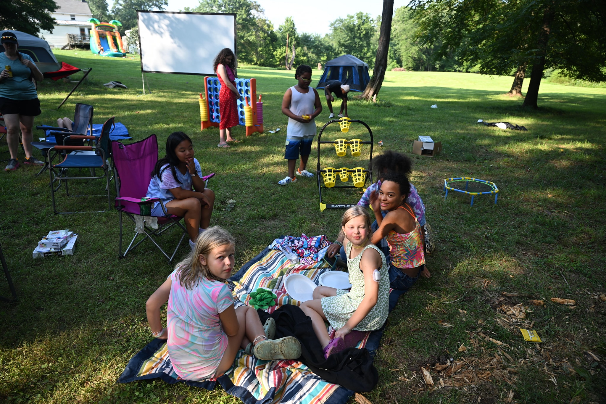 Kids relaxing on the lawn with the movie screen and lawn games set up behind — Campout 2024