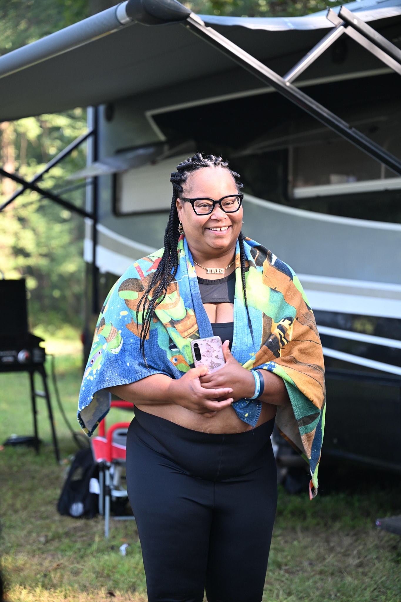 Wrapped in a colorful blanket and smiling in front of the RV — Campout 2024