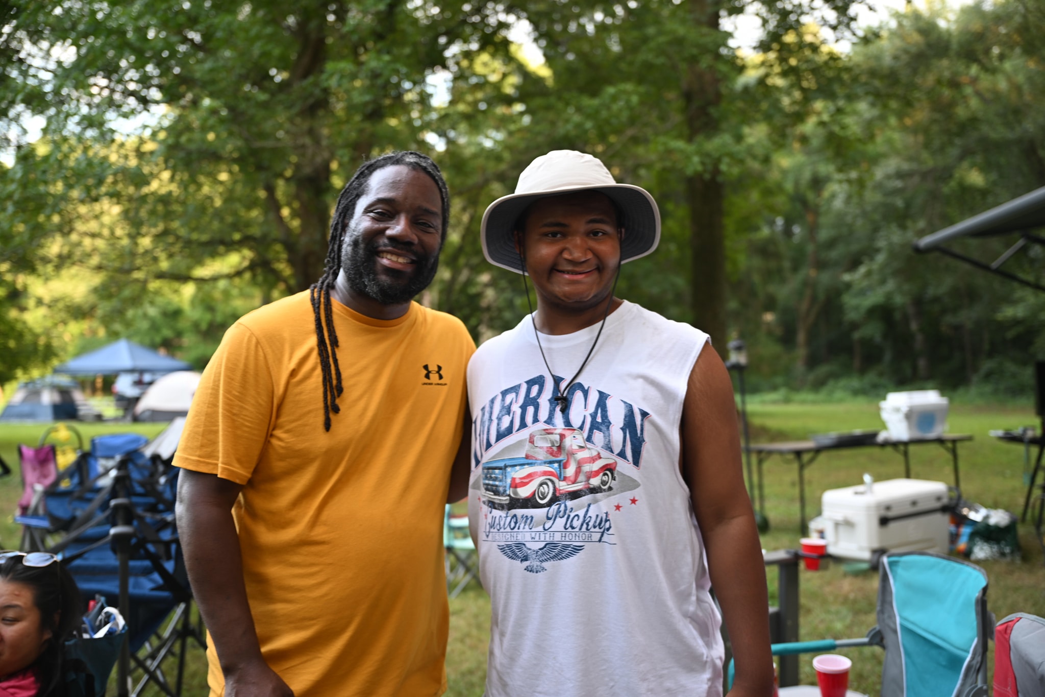 Two friends smiling together on the open lawn at the campout — Campout 2024
