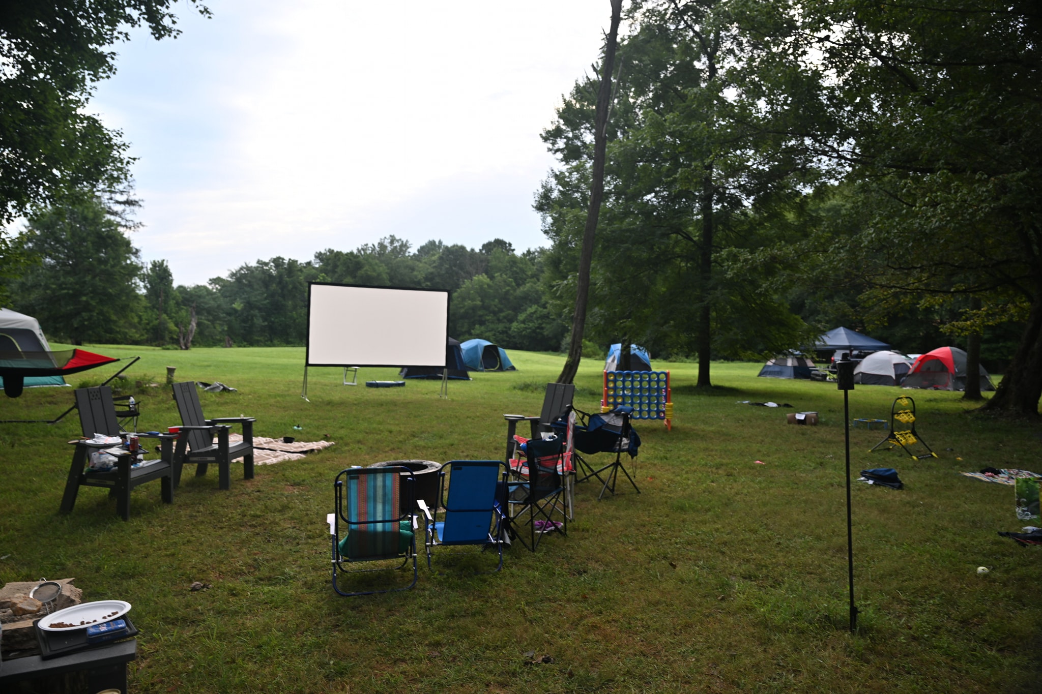 Daytime setup with movie screen, camp chairs, and lawn games all ready — Campout 2024