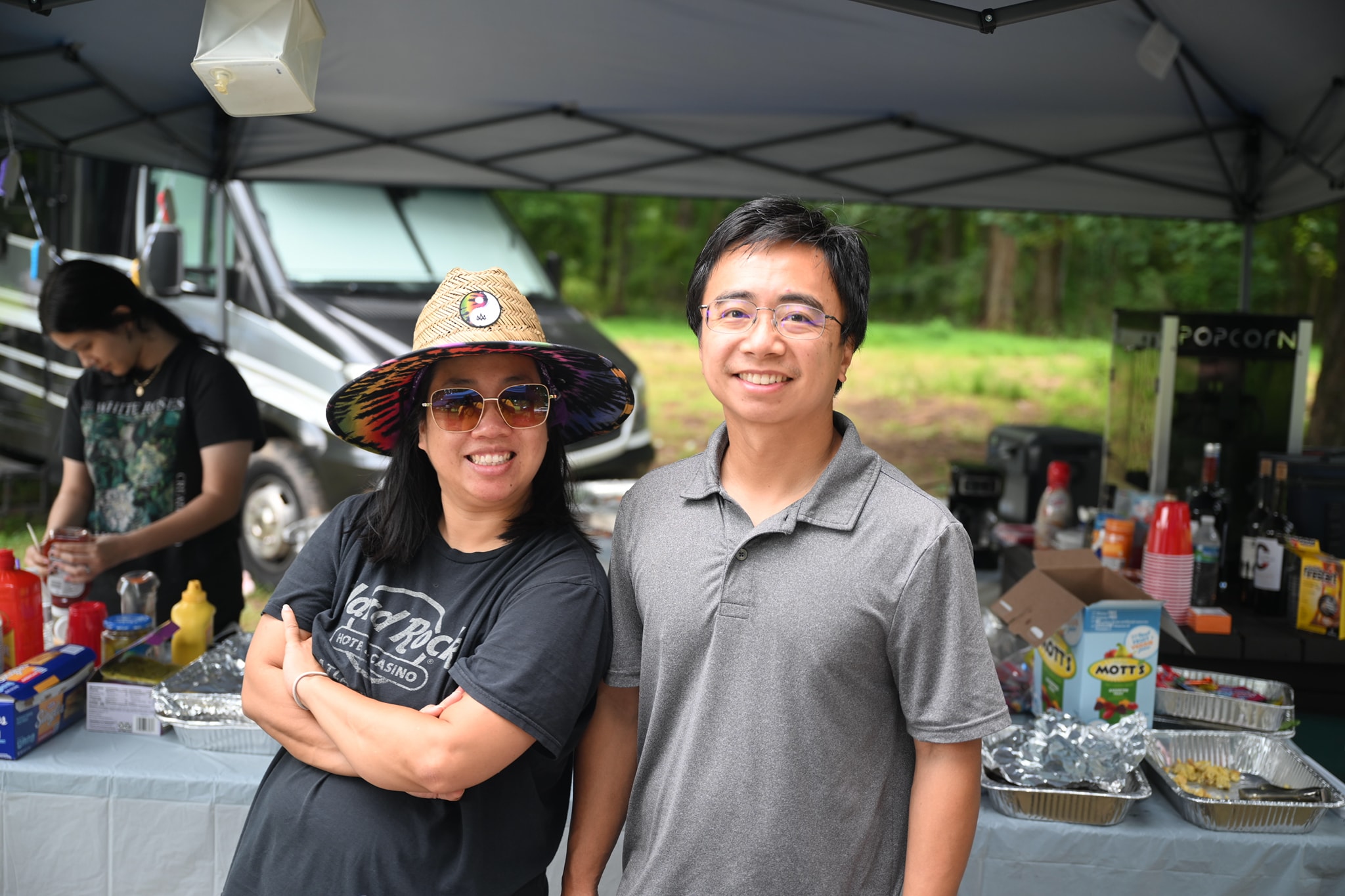 A couple smiling behind the food table with the popcorn machine nearby — Campout 2024