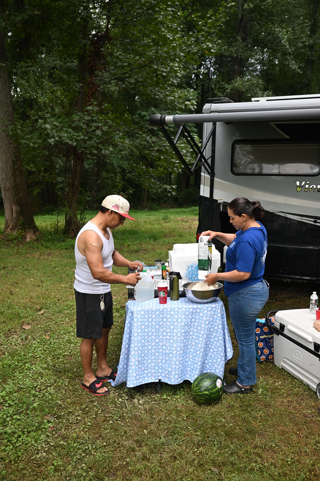 Preparing drinks beside the RV with a whole watermelon on the table — Campout 2024