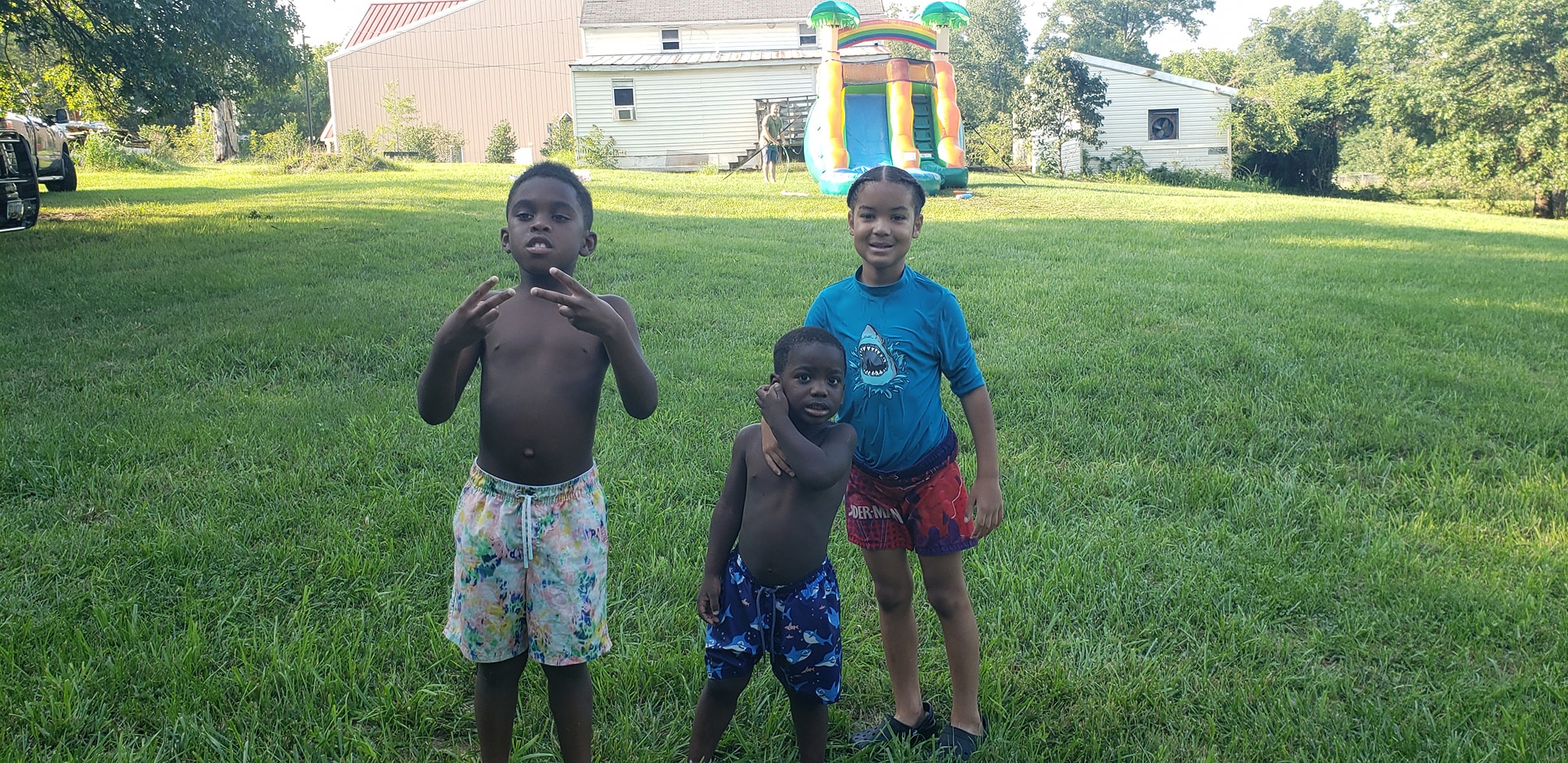 Kids posing on the lawn with the inflatable water slide behind them — Campout 2024