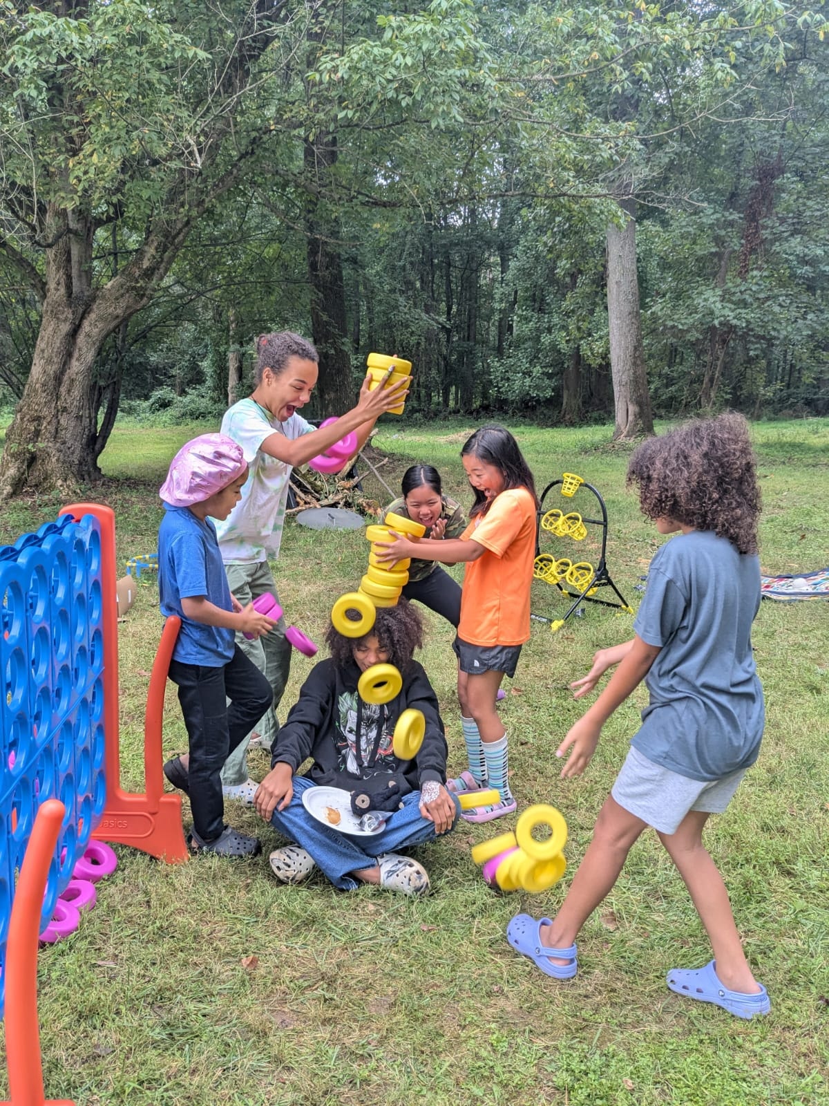 Kids laughing and playing ring toss with foam rings on the lawn — Campout 2024