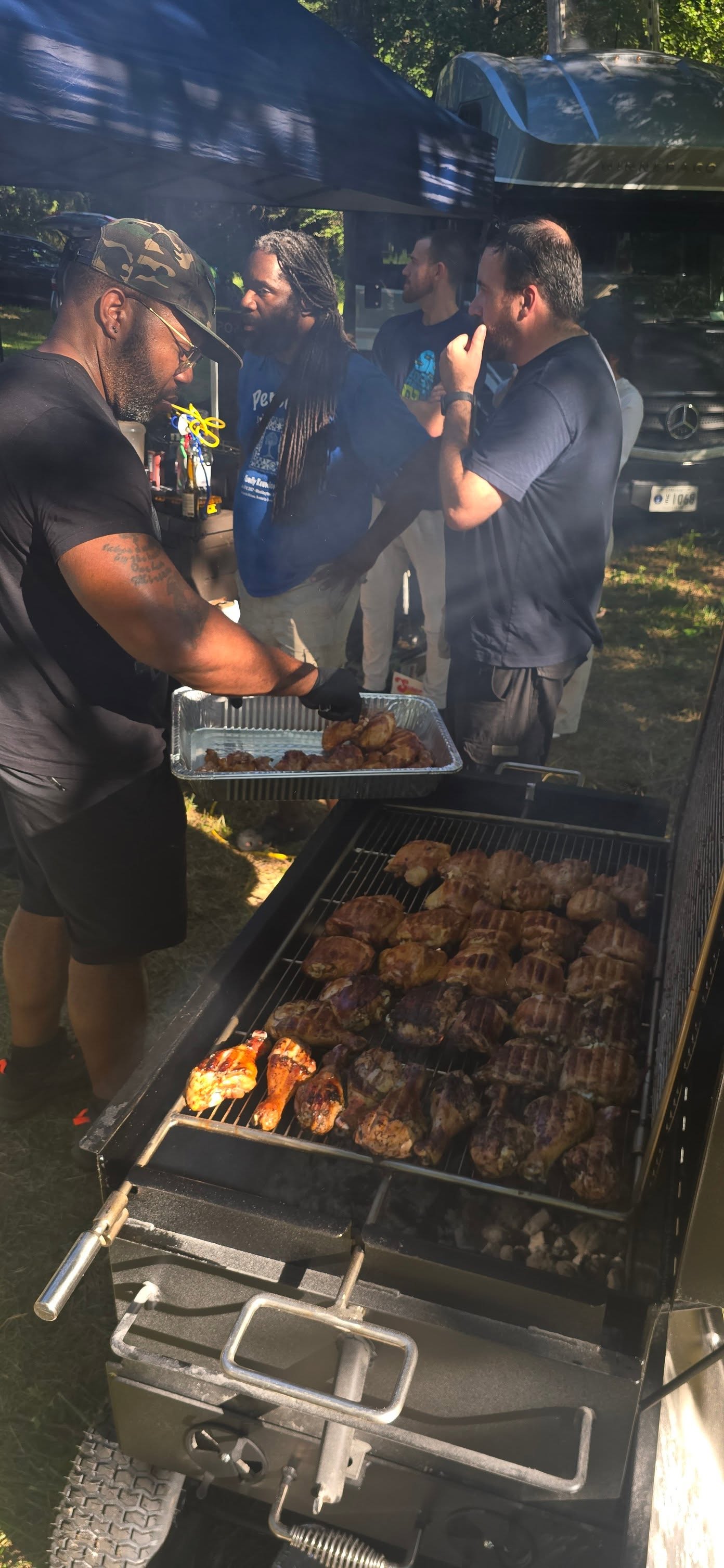 Loading a pan of smoked meat near the smoker, ready to serve — Campout 2025