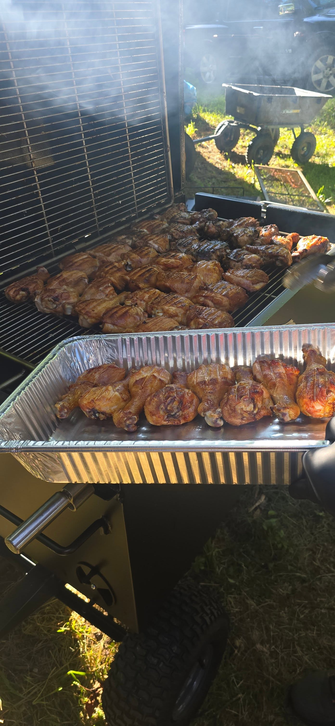 Smoked chicken piled into a foil pan fresh off the grill — Campout 2025
