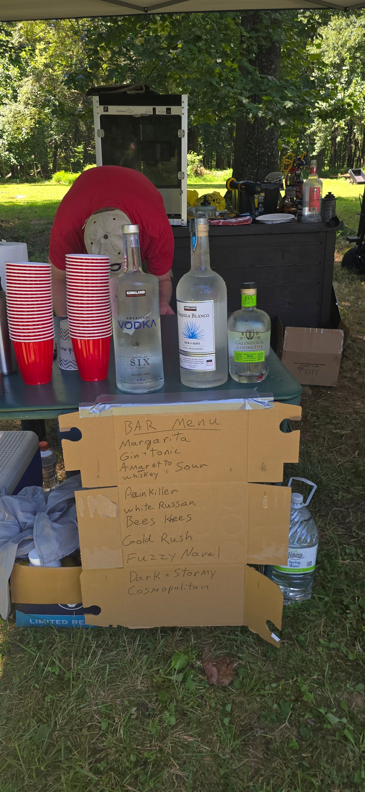 Bar station with liquor bottles, red cups, and a handwritten menu — Campout 2025