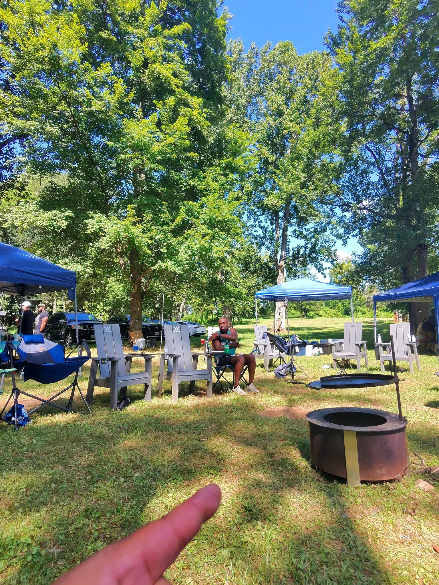 Fire pit and Adirondack chairs set up in the wooded yard — Campout 2025