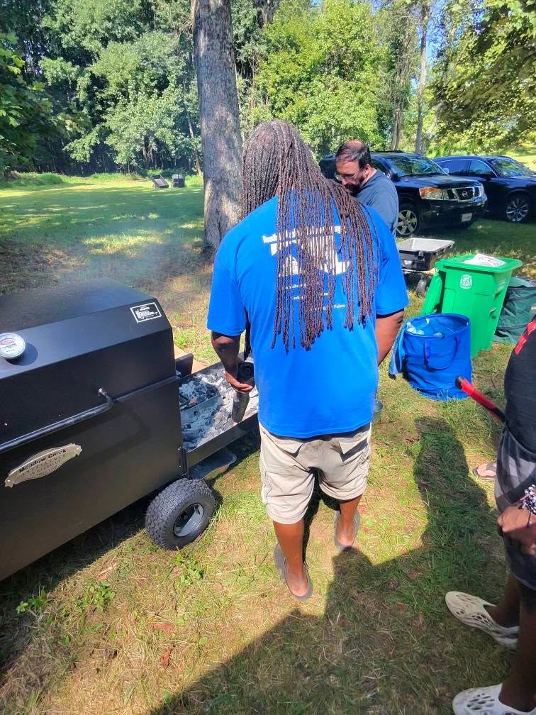 Tending the smoker in the wooded backyard — Campout 2025