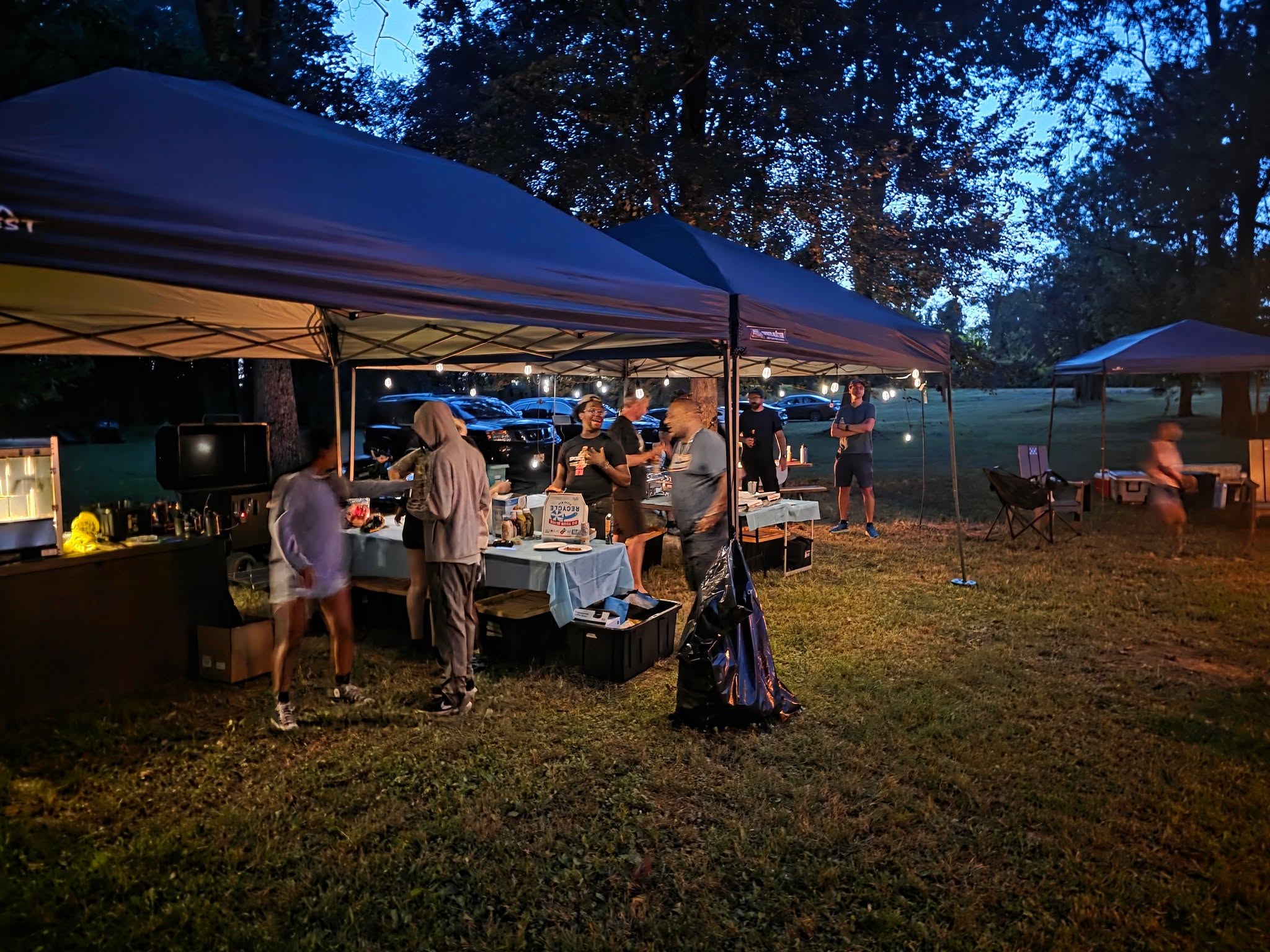 Guests socializing under lit canopy tents late into the night — Campout 2025