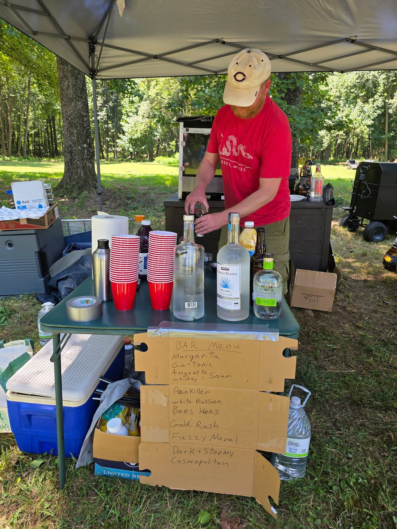 Bartending at the outdoor bar station with the cocktail menu on display — Campout 2025