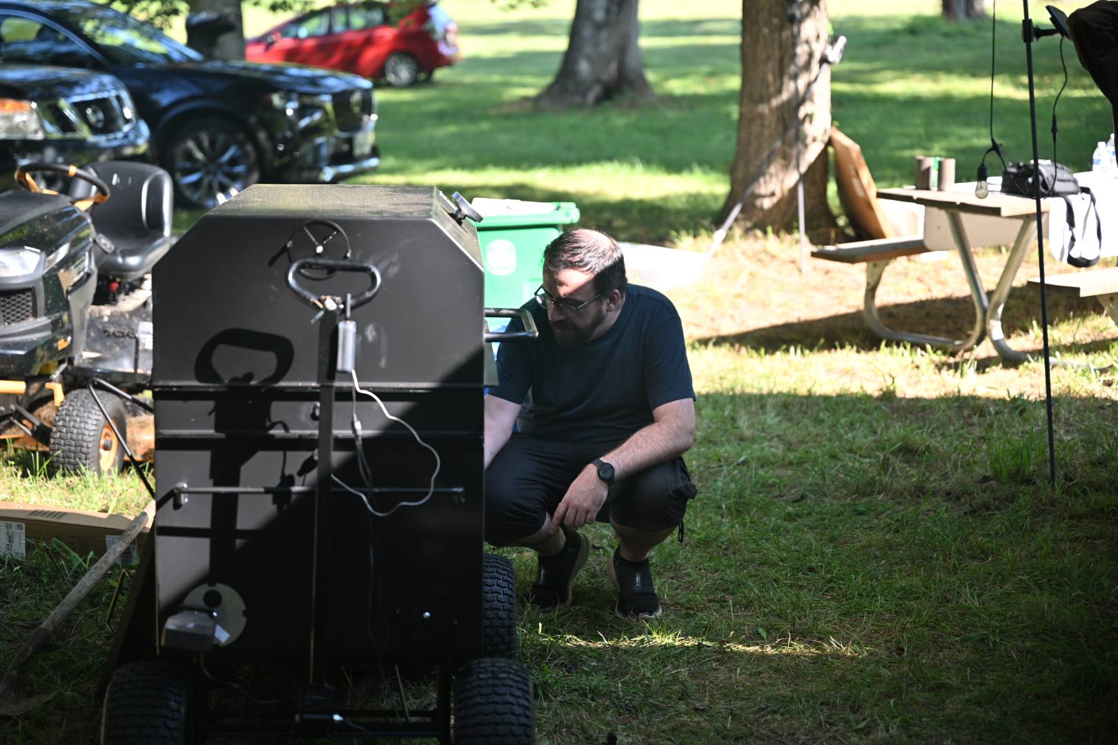 Crouching beside the smoker to check on the meat — Campout 2025