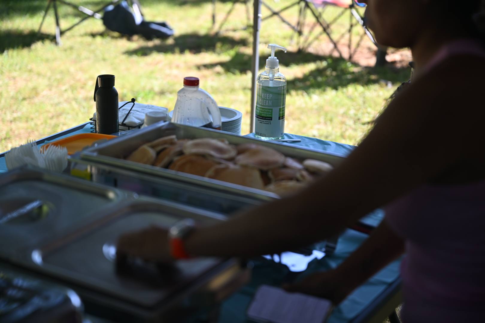 Cutting chicken at the catering table in the shade of the canopy — Campout 2025
