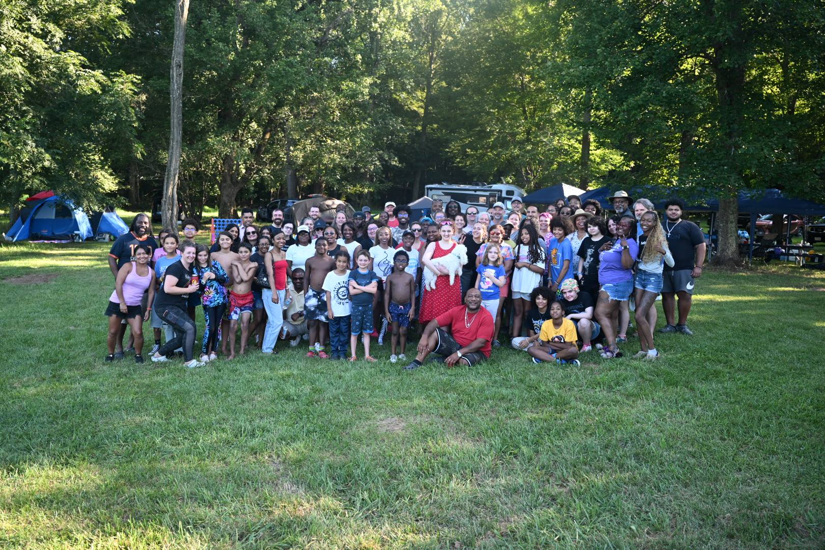 Group photo on the lawn surrounded by trees and tents — Campout 2025