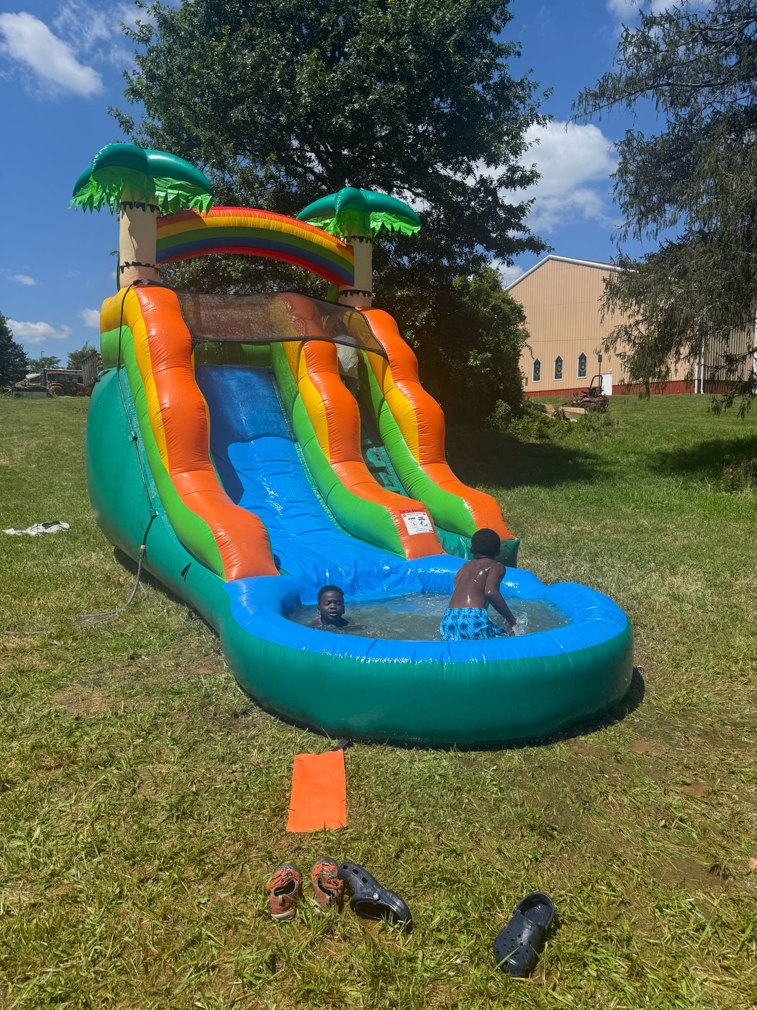 Kids splashing in the pool at the base of the inflatable water slide — Campout 2025