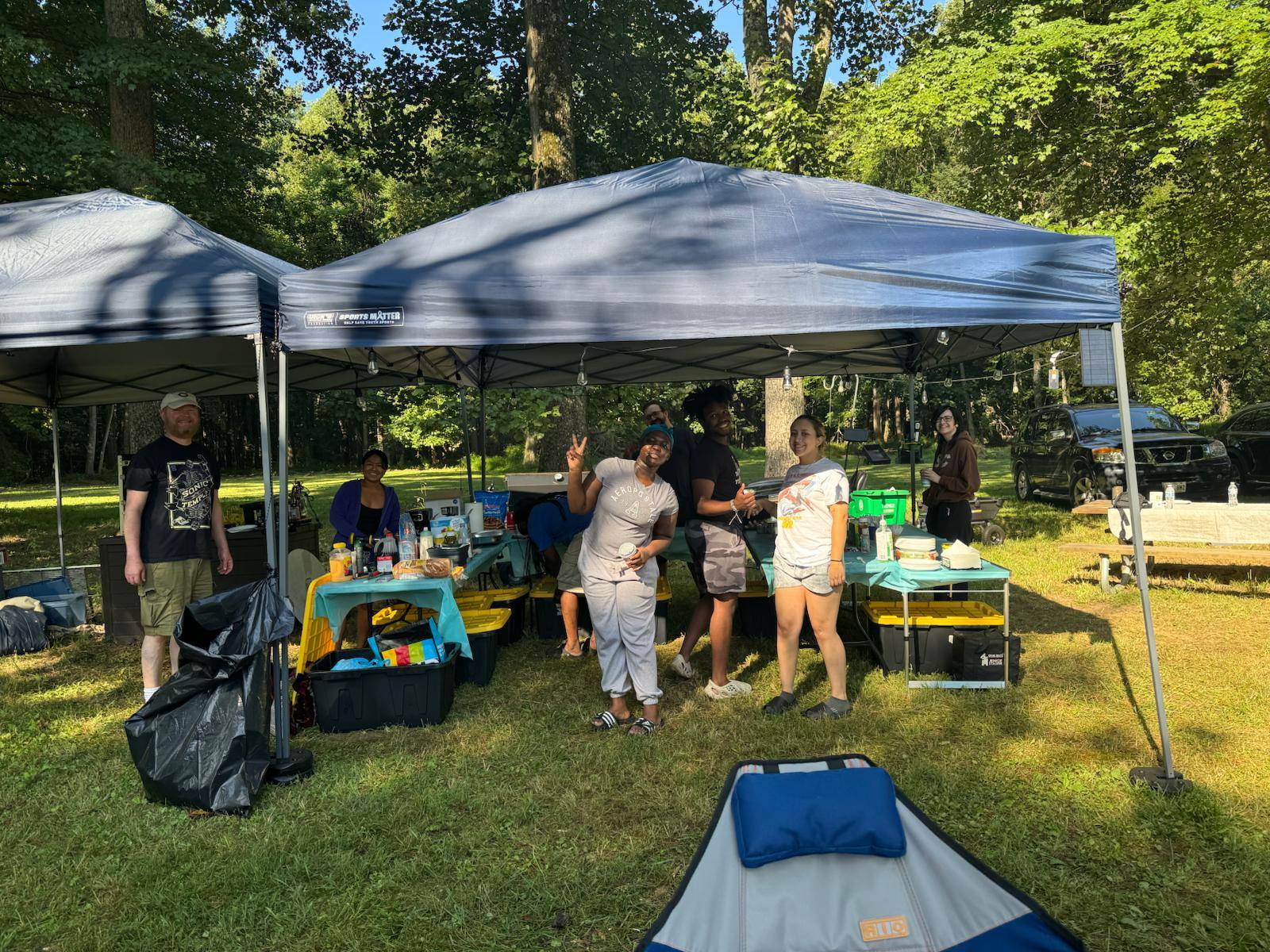 Guests mingling around the food canopy in the wooded backyard — Campout 2025