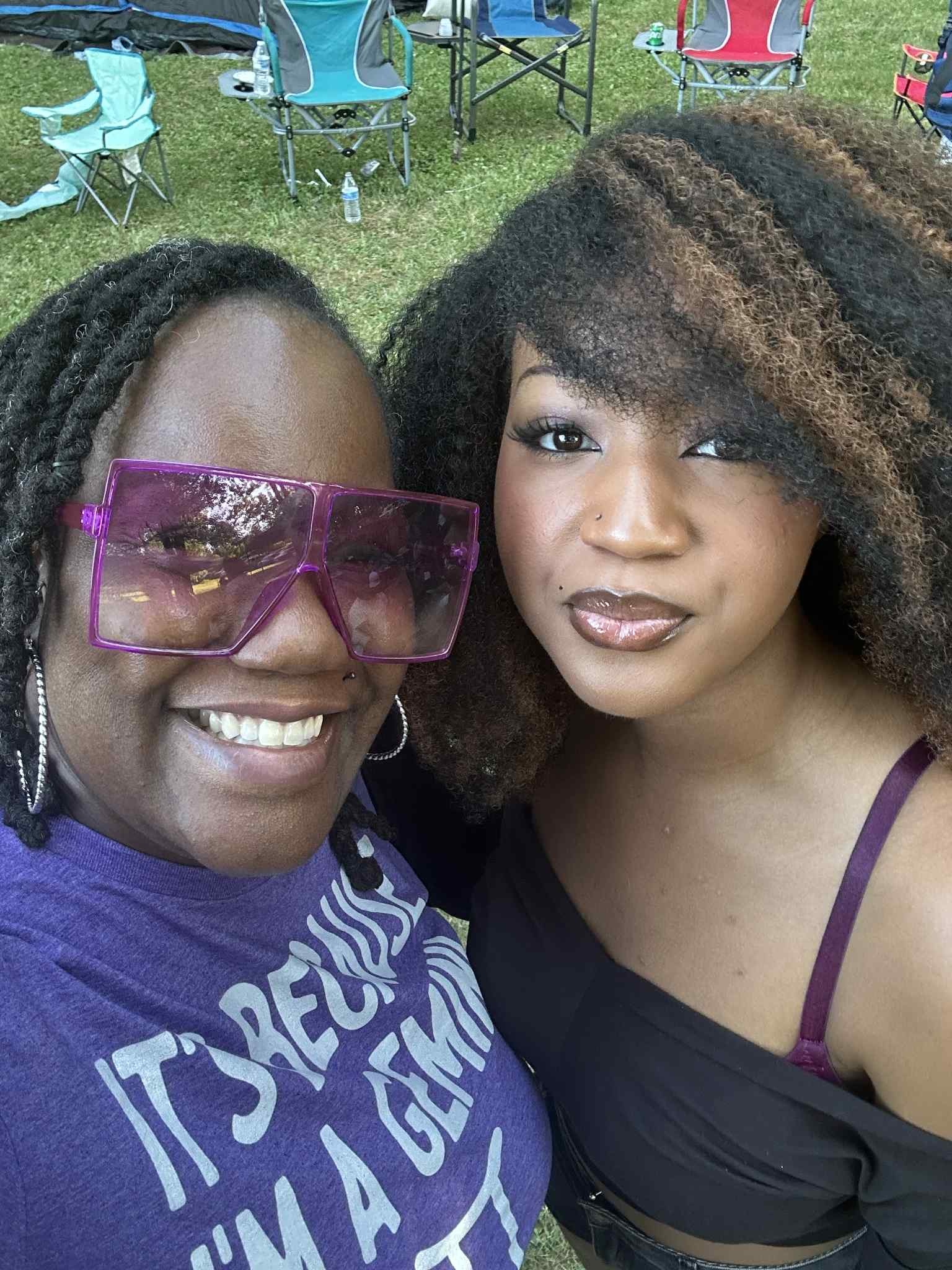 A sunny selfie with camp chairs and the open lawn behind — Campout 2025