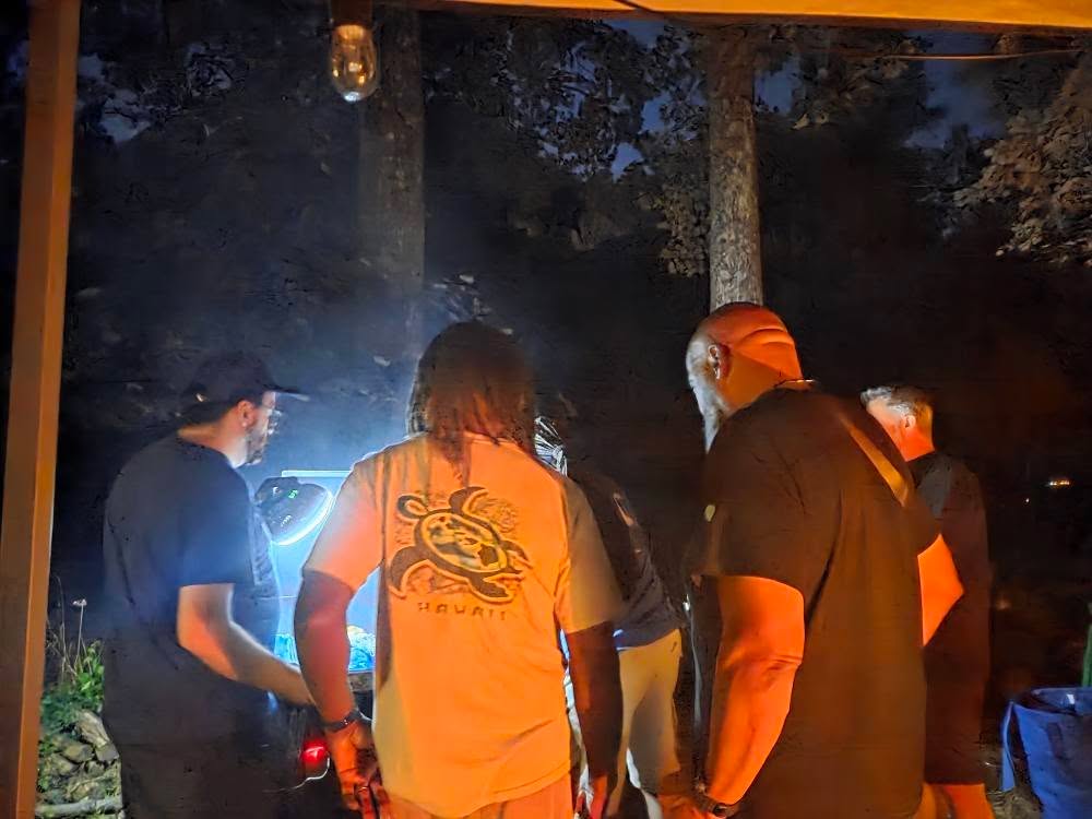 Working the overnight smoker under a bright work light — Campout 2025