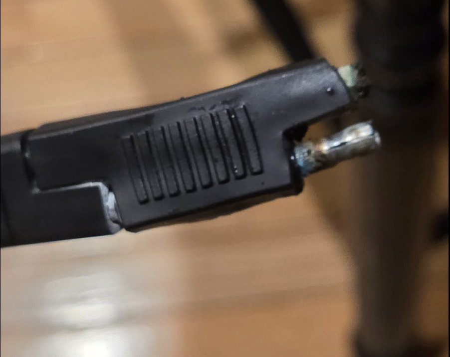 Close-up of the failed SAE solar connector, its housing melted back from the terminals with visible corrosion on the contacts