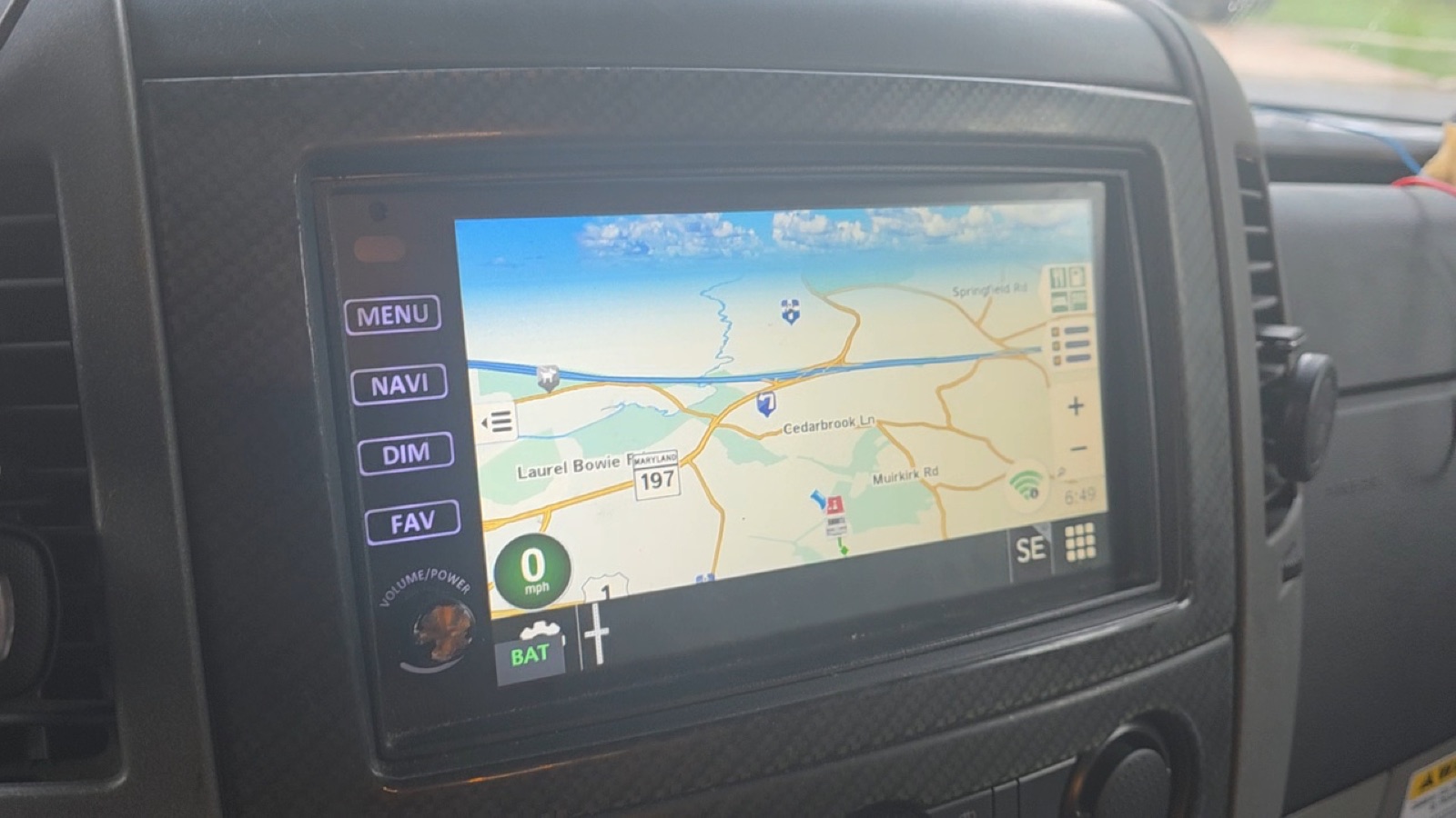 The Xite head unit showing the Rand McNally navigation map with a small green BAT button in the bottom-left corner